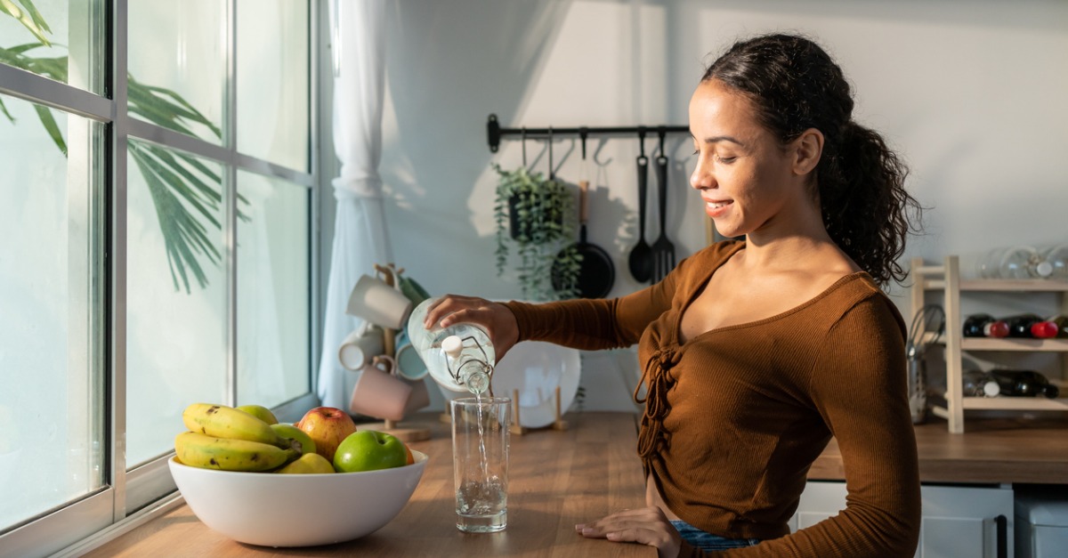 Young woman pouring water into glass