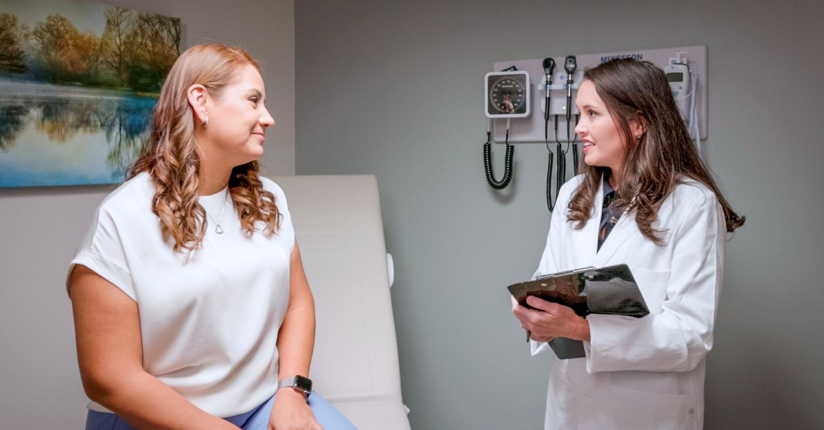 Dr. Ashley Ray (right) talking to a patient at University Cancer & Blood Center